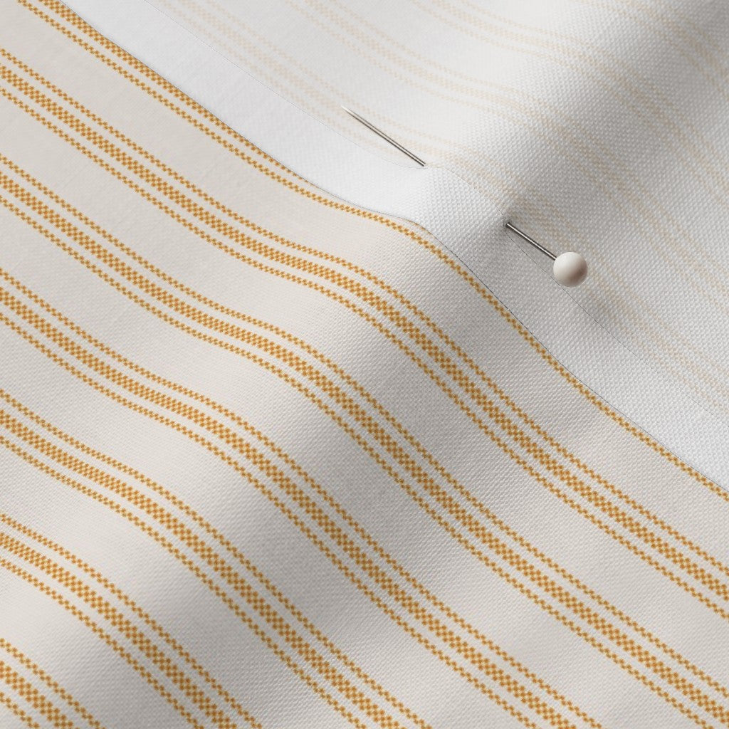 close up of classic mattress ticking stripe fabric in saffron marigold on cream white