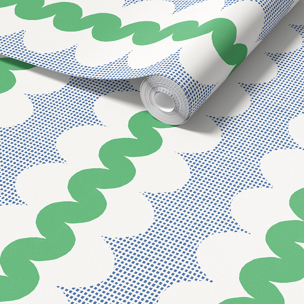A roll of wallpaper with a retro pattern of green wavy lines, blue square dots, and white oval shapes, shown partially unrolled on a white surface.