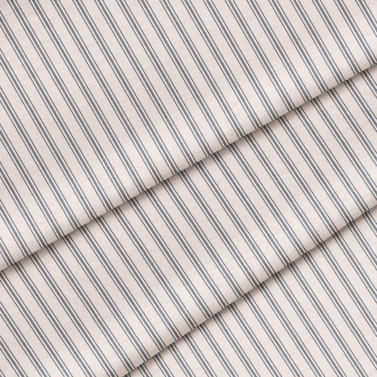 A close-up of navy blue striped fabric with a classic ticking pattern. The fabric is folded onto itself.