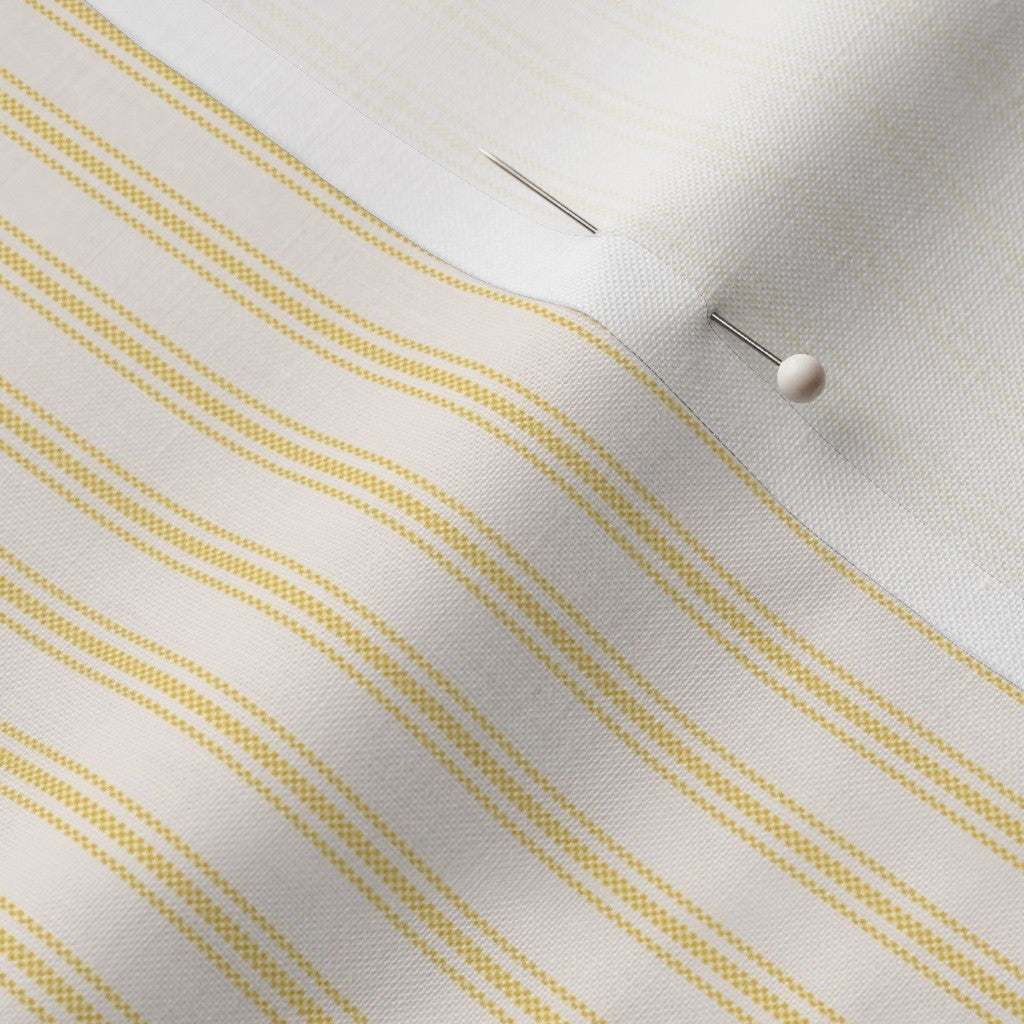 close up of mattress ticking stripe fabric in sunny yellow on off white
