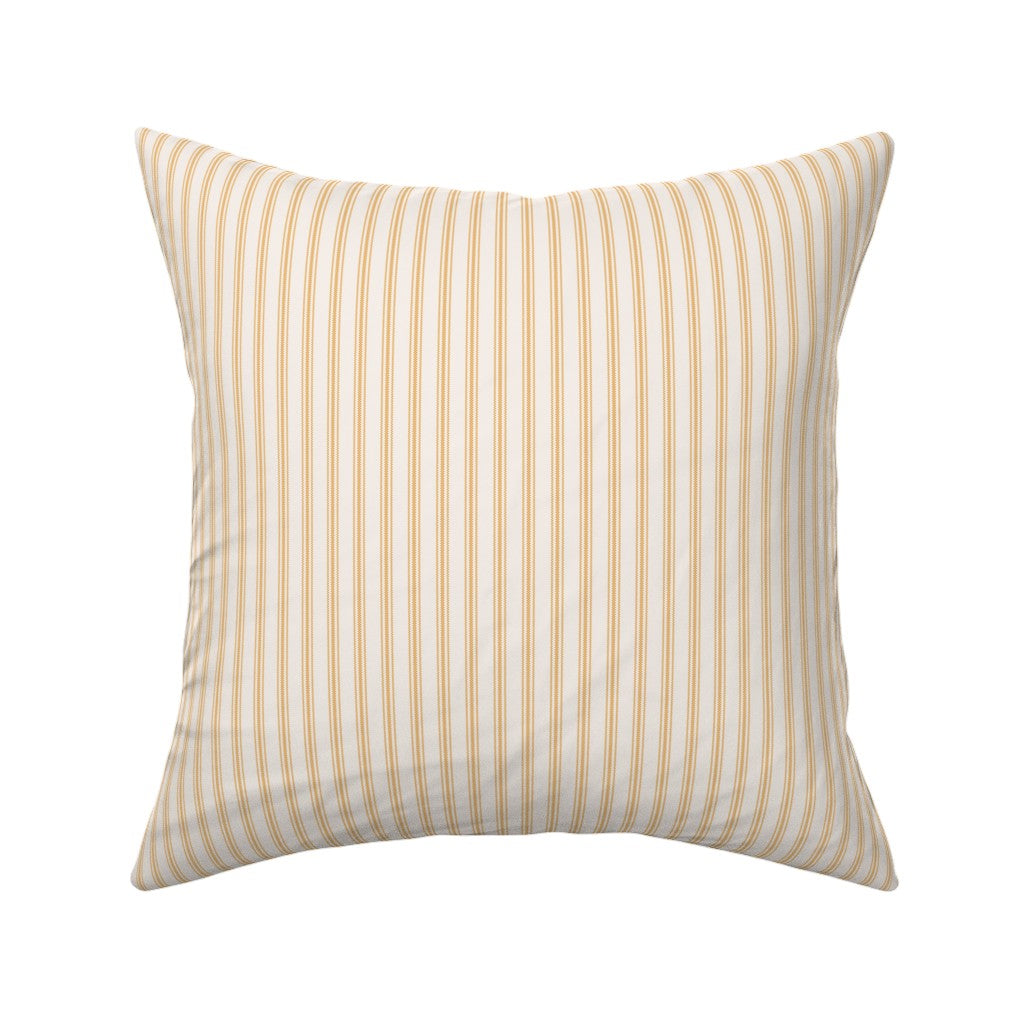 Classic mattress ticking stripe fabric shown on a square pillow. The color of the stripe is saffron on off white.