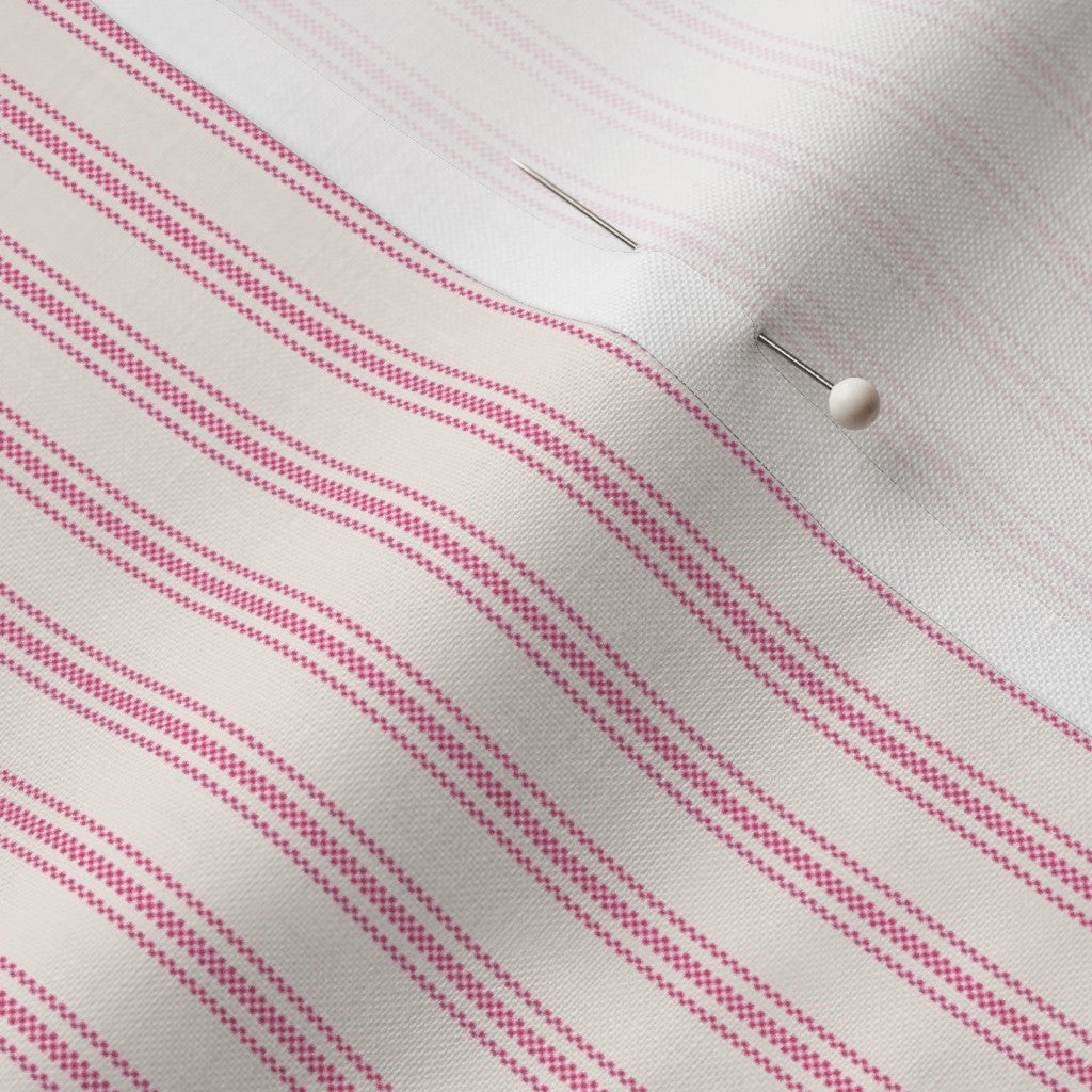 close up of classic mattress ticking stripe fabric in hot pink on cream.
