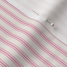 close up of classic mattress ticking stripe fabric in hot pink on cream.