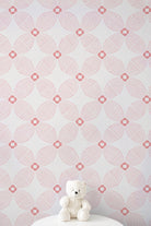 Pink and white geometric patterned wallpaper with a small white teddy bear sitting on a white surface at the bottom.