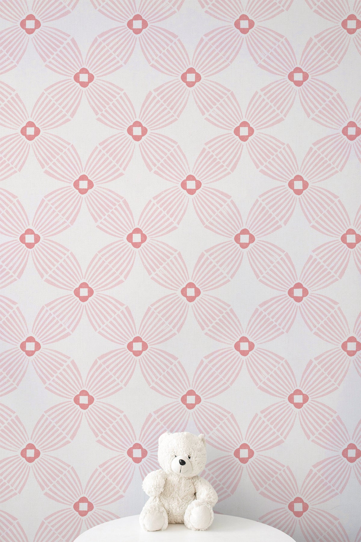 Pink and white geometric patterned wallpaper with a small white teddy bear sitting on a white surface at the bottom.