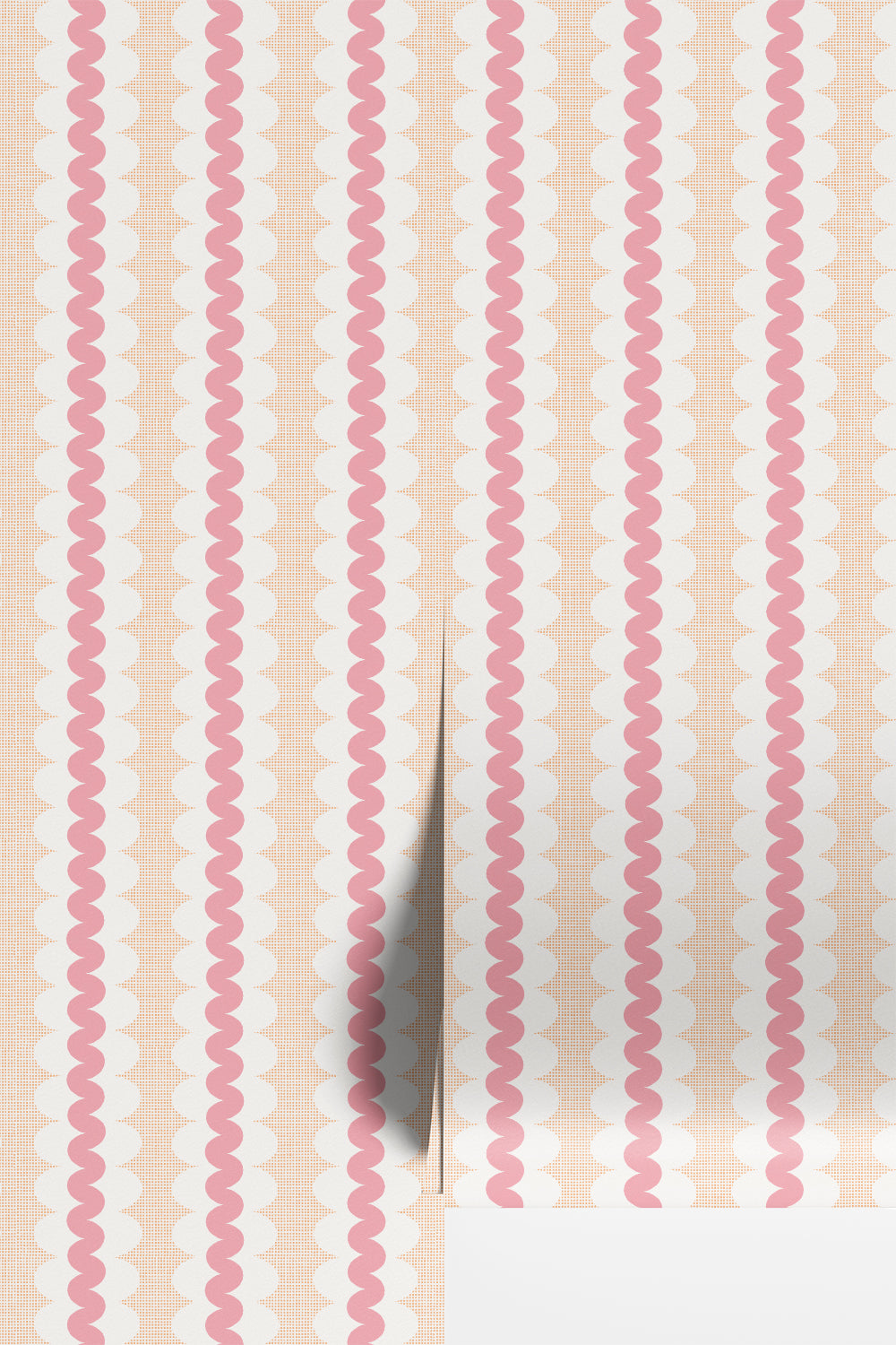 A close-up of wallpaper or fabric with a repeating vertical pattern of pink wavy lines over a nectarine and white scalloped background, with a folded corner showing a light gray underside.