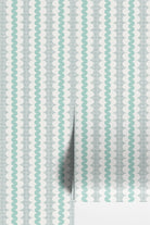 A close-up of wallpaper or fabric with a repeating vertical pattern of mint green wavy lines on a white background with a subtle light gray grid texture.