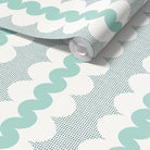A roll of wallpaper with a repeating pattern of aqua green wavy lines over a white background with a fine teal halftone dot grid, shown partially unrolled.