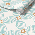 A roll of wallpaper with a repeating mid-century modern fan pattern in light blue and warm tan on an off-white background, shown with the top corner rolled back.