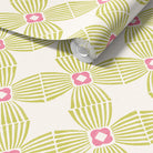 A roll of wallpaper with a repeating geometric pattern in olive green and pink on a warm off-white background, shown partially unrolled.
