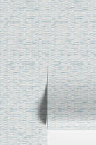 Light blue and white textured wallpaper with a subtle horizontal pattern, shown with a vertical fold casting a soft shadow.