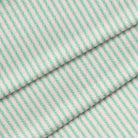Close-up of a kelly green ticking stripe fabric. The fabric is folded onto itself.