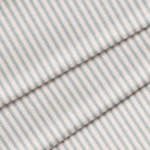 Close up of a classic ticking stripe in stormy gray on off white. The fabric is folded onto itself.